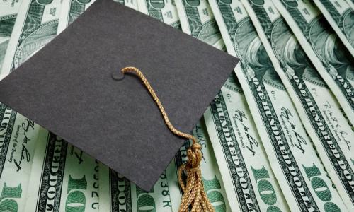 a graduation cap atop $100 bills
