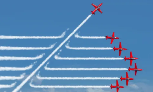 red planes flying in a straight formation with jet streams behind with one plane cutting through on a diagonal