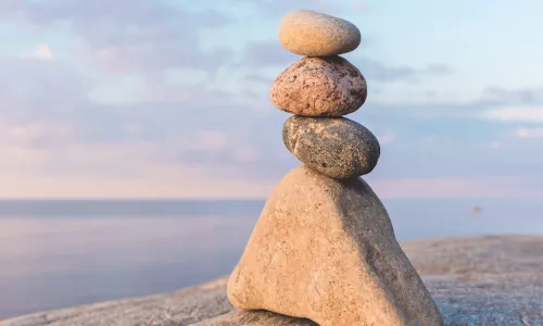 a cairn or stack or rocks on a beach with a beautiful blue sky