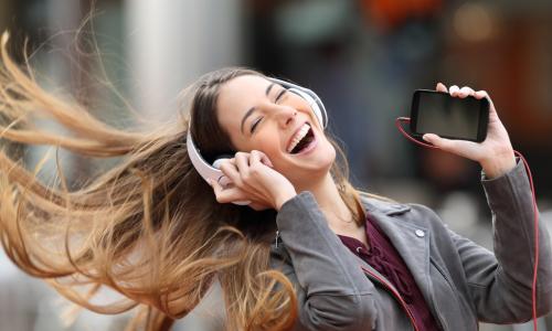 young woman dancing with cell phone and hair flying