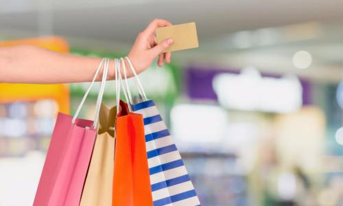 woman with several colorful shopping bags holding credit card