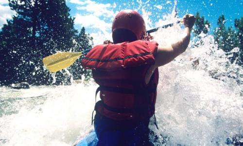 male kayaker paddling through rapids