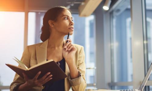 woman staring off thoughtfully into the distance while holding an open book