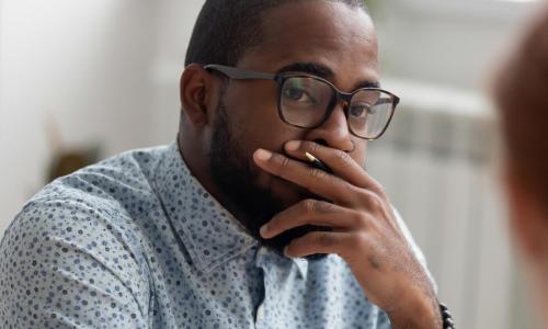 Unpleasantly surprised african-american businessman listening female caucasian coworker 