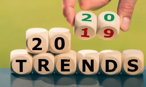 hand flipping wooden dice that spell 2019 trends to 2020 trends