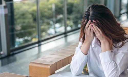 anxious female employee holding her head while working alone at a table