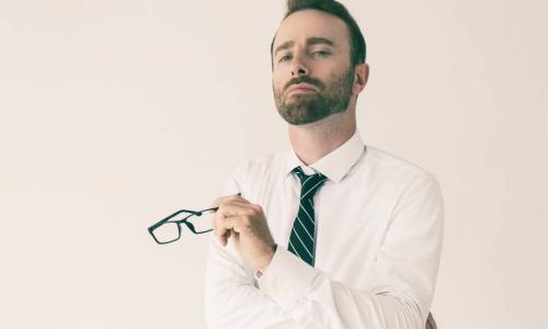 arrogant businessman holds glasses while looking haughty and condescending 