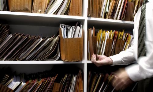 man retrieves old file off shelves