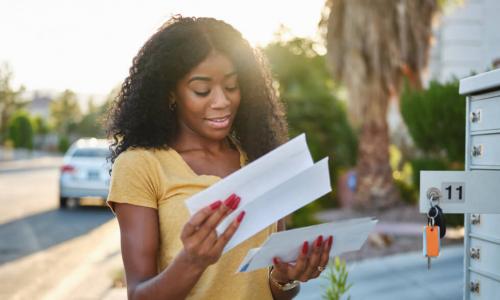 young African American woman checking her mail at bank of mailboxes