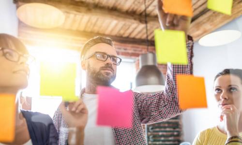 business people brainstorming with sticky notes on glass wall