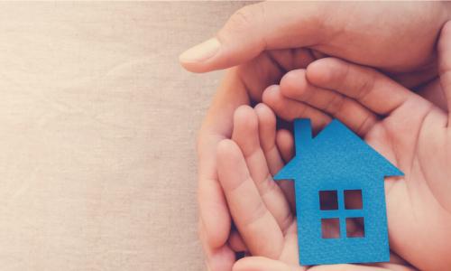 adult and kid hands hold blue paper house