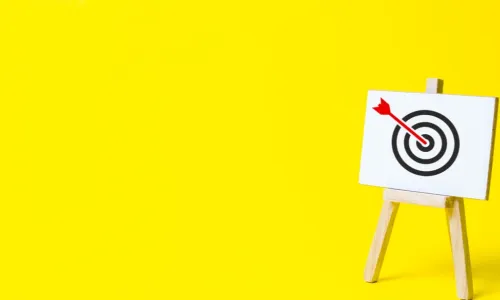 red arrow on target on easel on yellow background