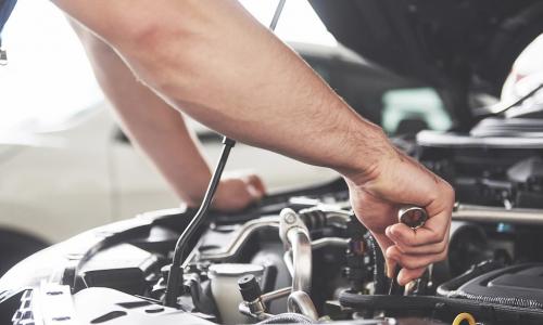 mechanic works on tuning up car engine