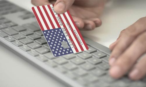 man making online payment using credit card with U.S. flag keyboard