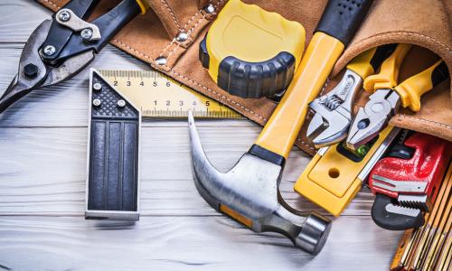 hammer and leather belt with pouches full of tools on wood surface