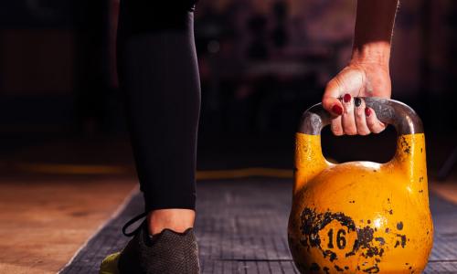 athlete exercising with a yellow kettlebell