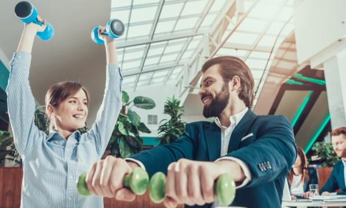 Business People in Office Interior Working with Dumbbells
