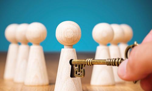 hand inserting ornate brass key into keyhole of wooden people figure