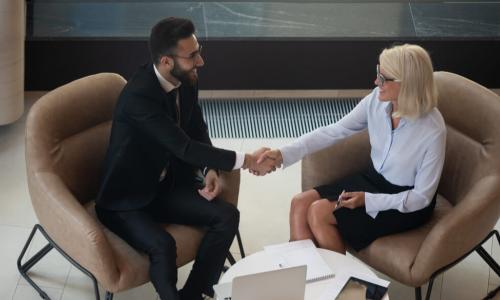 mature businesswoman shakes hands with younger businessman