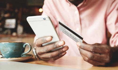 man in a pink shirt in a coffee house making a payment