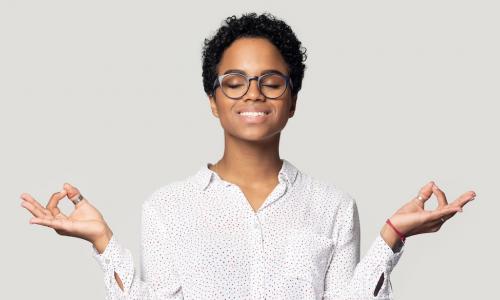 calm young Black businesswoman meditating to reduce stress