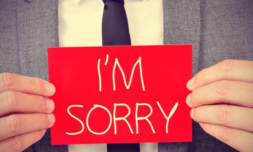 man with red sign saying I’m sorry