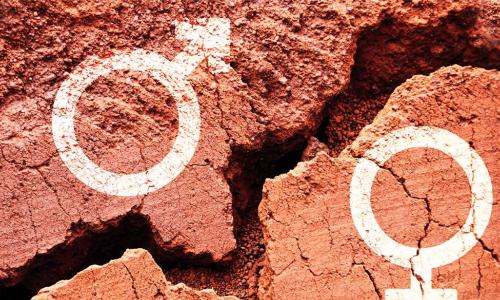 chalk symbols representing male and female gender on red clay earth on opposite sides of a chasm