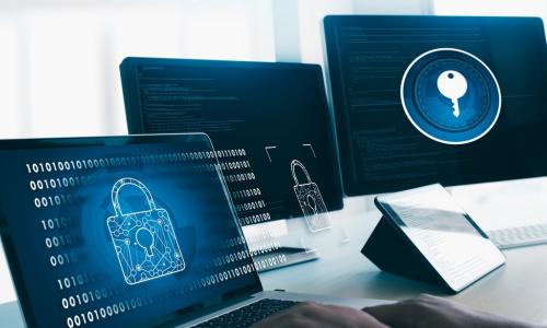 man working with three screens showing locks and data