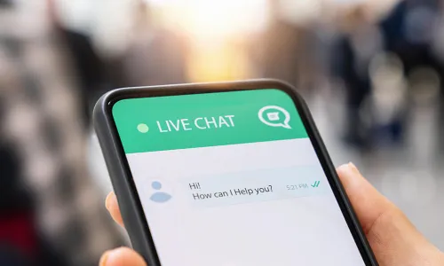 manicured hand holding smartphone with live chat support app asking how it can help
