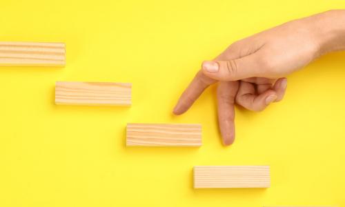 woman’s fingers walking up wooden block steps