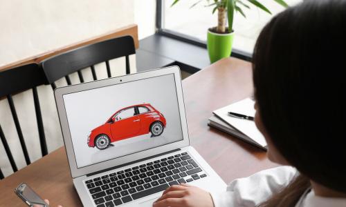 woman using a laptop and a phone to do car shopping