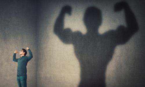 confident man flexing muscles in his shadow