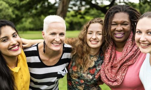 diverse group of women with arms around each other being supportive