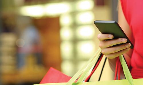 woman in red dress holding colorful shopping bags and a smartphone