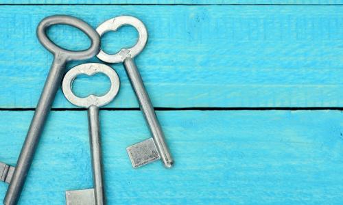 three old fashioned silver keys on a blue wooden background