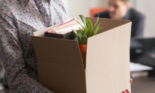 female employee carrying box of belongings as she prepares to leave office