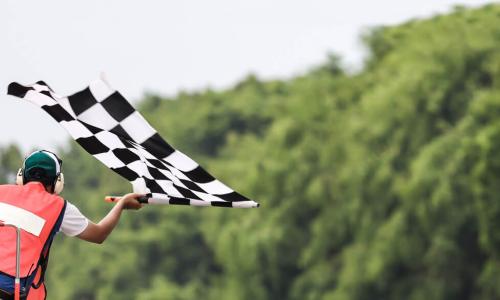 Back view of man holding checkered race flag