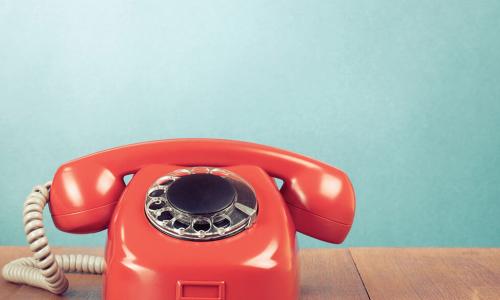 old fashioned red rotary phone on wooden surface