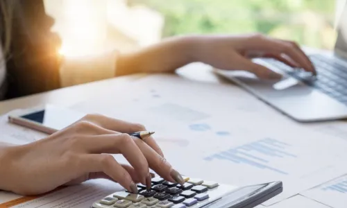 woman using calculator and laptop to do accounting