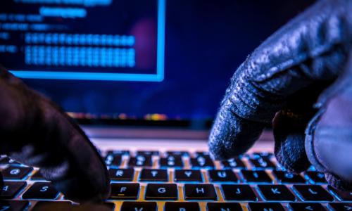 gloved hacker hands with keyboard and screen