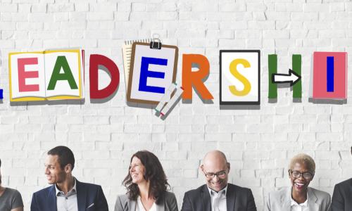 diverse group of business people sitting against a wall with the word Leadership
