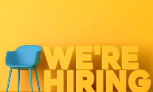 yellow wall blue chair we're hiring