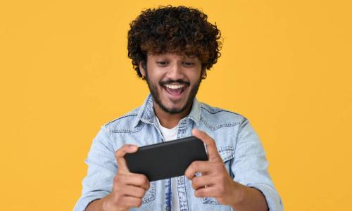 excited young Indian man looking at a phone