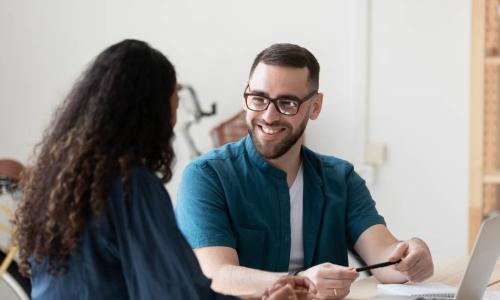 smiling male and female coworkers brainstorm together at desk