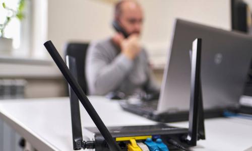 wireless router with ethernet cables and man working in the background