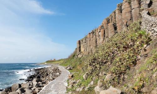 stone paved pathway runs along shore at cliffside beach