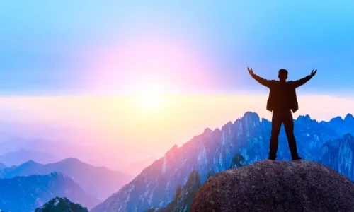 man with outstretched arms atop mountain