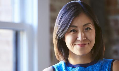 businesswoman CEO standing by office window smiles confidently