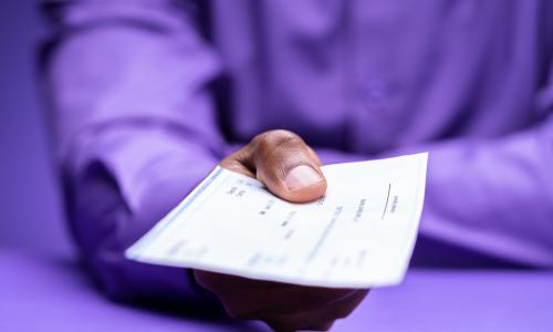 man in purple shirt holding out check for loan