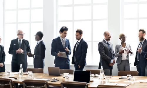 diverse group of board members mingles after meeting